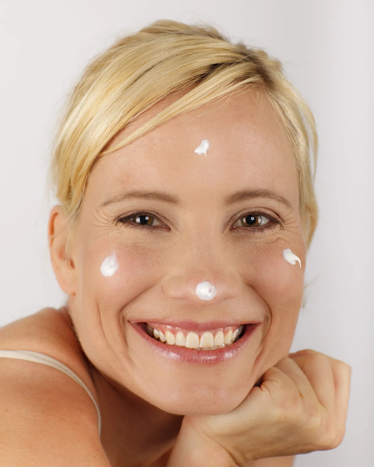 Frau mit Cremetupfern im Gesicht