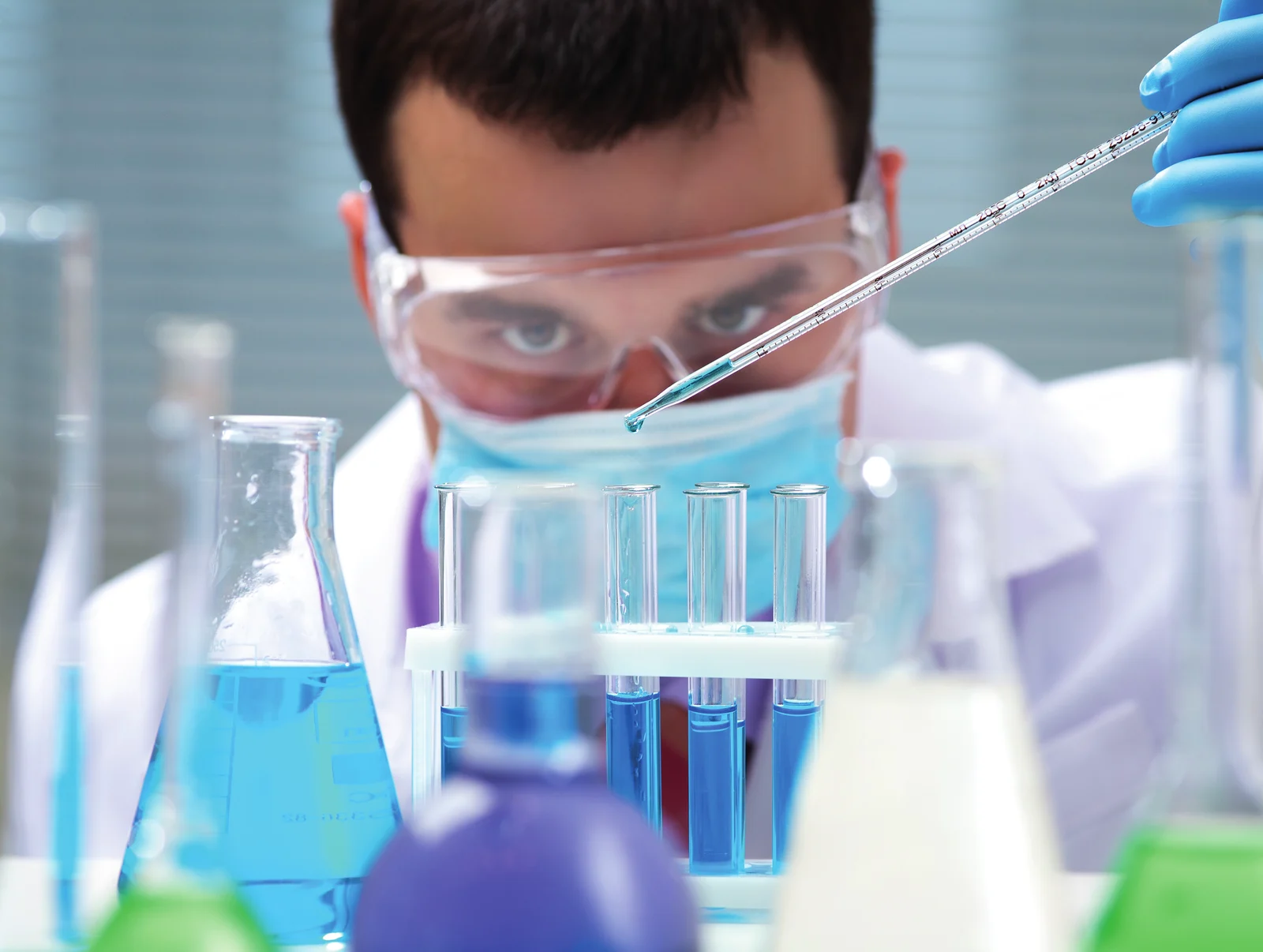 Chemiker mit Pipette und Reagenzgläsern im Labor